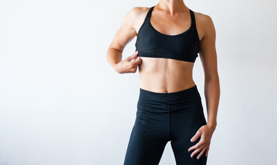 fit body fitness girl. Slender woman in black fitness underwear standing indoors in room at daytime.