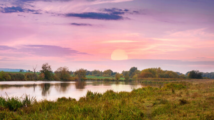 Fototapeta na wymiar Picturesque landscape with river and sun over horizon, sunset over river