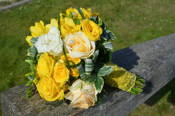 Wedding bouquet of yellow roses on wooden bench