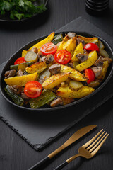 Hot vegetable salad in a plate on a wooden table.