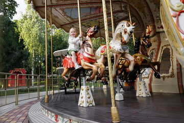 little girl on a French carousel in an amusement park