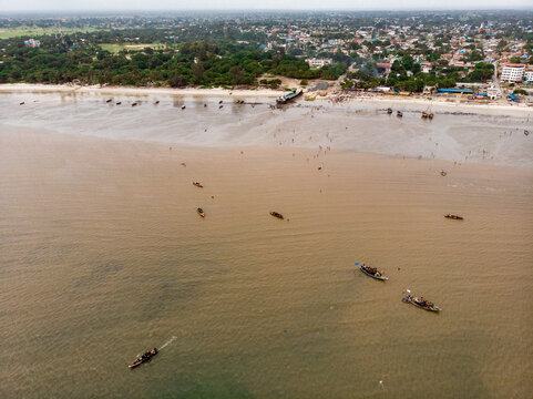 An aerial shot from Bagamoyo, Tanzania. Indian Ocean Coast with Vessels and Crowd of people Carrying Catch from fishermans boats at Low Tide