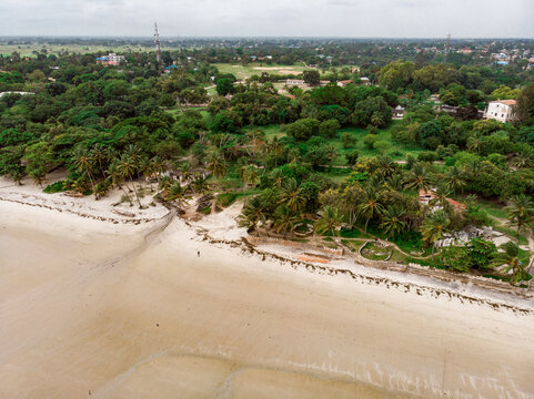 An aerial shot from Bagamoyo, Tanzania. Indian Ocean Coast with Vessels and Crowd of people Carrying Catch from fishermans boats at Low Tide