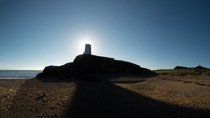 Fototapeta na wymiar North Wales coast with a sun behind the Llanddwyn Lighthouse, UK