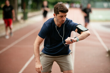 Young man checking his heart rate during work out. Young man exercising on the athletics track	