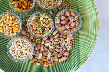 Pile of legumes including beans, peas, lentils arranged on a green plate.