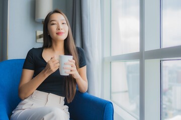 Portrait beautiful young asian woman hold coffee cup on sofa chair