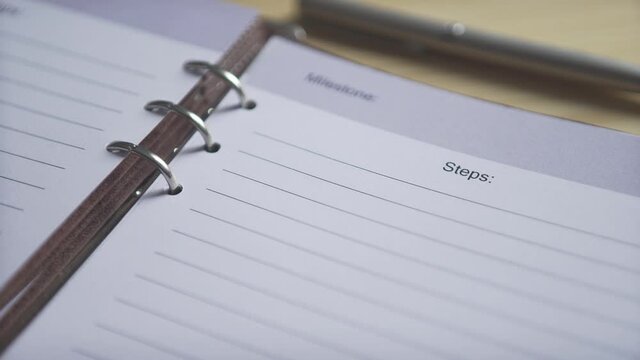 Close up shot of empty white paper lined pages of bullet journqal planner brown leather note book pad on wooden table