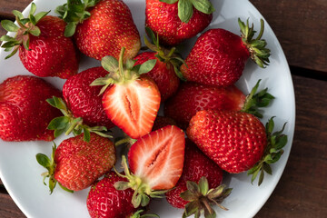 Ripe fresh strawberries on a white plate close-up.