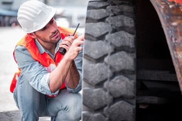 Engineer or mechanic man checking and maintenance forklift wheel tyre at container box cargo and using walkies talkie call with his supporter to confirm inspect before use. © totojang1977