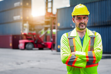 Confident Caucasian man engineer wearing yellow safety helmet using walkies talkie call to driver and check for control loading containers box from Cargo freight ship for import and export, transport
