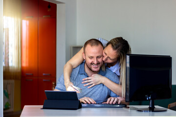 Happy young Caucasian couple shopping online through tablet using credit card at home. Man and women with digital tablet and credit card buying online. Family couple looking at tablet computer at home