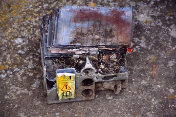 Polluting garbage. Car battery used as a destroyed and abandoned electric shepherd in the field.
