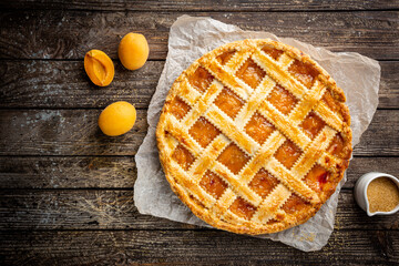 Summer apricot or peach pie homemade on wooden background, top view. Delicious fruit dessert. Fruit cake. Copy space.