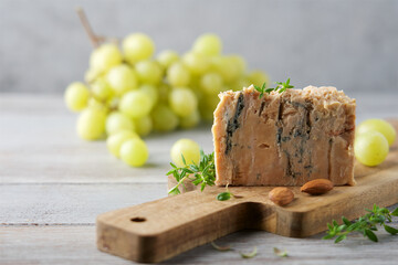 French Roquefort cheese with mold on a cutting board with grapes and nuts. Traditional French...
