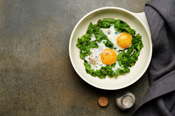 Fried eggs with kale in frying pan. Healthy morning breakfast