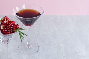 Non-alcoholic pomegranate cocktail with rosemary on a light pink background. Natural healthy drink.