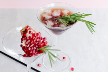 Cold non-alcoholic pomegranate cocktail with rosemary on a light pink background. Natural healthy drink