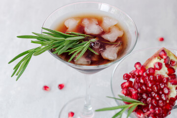 Cold non-alcoholic pomegranate cocktail with rosemary on a light pink background. Natural healthy drink
