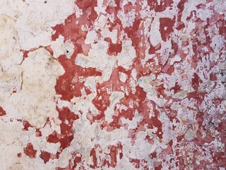 Damaged wall texture. Red and pale yellow paint peeling off the wall.