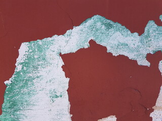 Damaged wall texture. Red and green paint peeling off the wall.