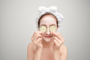 Attractive young woman covering her eyes with cucumbers on a blue background. Clay mask.
