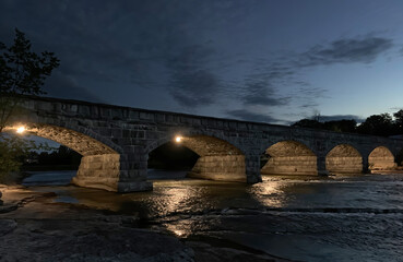 Fototapeta na wymiar Pakenham Bridge, a five arch stone bridge that crosses the Mississippi River at night in Pakenham, Canada