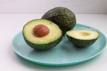whole and sliced avocado on a blue plate