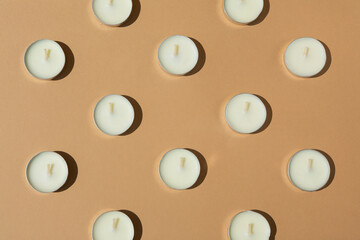 white candles on a beige background. Contrast lighting. Flat lay