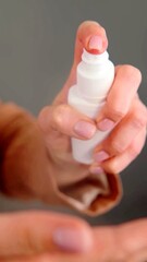 A close-up on the hands of a woman who is using a spray