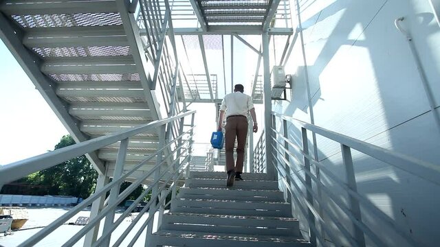 Attractive young man with high security bulletproof protected case climbing modern stairs outside the building