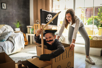 A boy is playing pirate in his room, his sister helps him