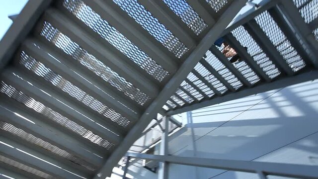Bottom camera 360 degree view on man in suit using climbing modern architecture stairs outside the building