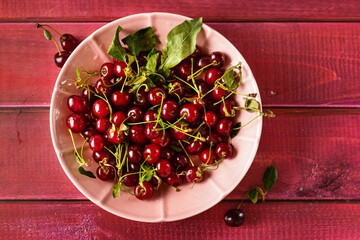 Dark red ripe and juicy cherries in a pink plate