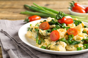 scrambled eggs with spinach and tomatoes on a white plate.