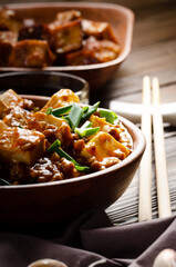 Chinese food mapo tofu dish with pork chives soy sauce sichuan pepper garlic and spices closeup on wooden table