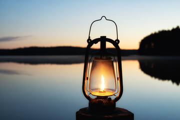 Vintage lantern near a lake. Beautiful calm lake on background. Night time. 
