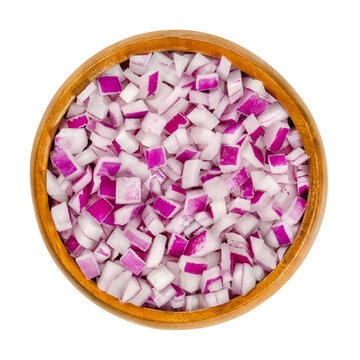 Diced red onions in wooden bowl. Cut cubes of onion cultivar Allium cepa, with purplish red skin and white flesh tinged with red. Closeup, from above, on white background, isolated, macro food photo.