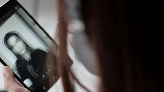 Pretty young lady watches her back and white selfie photographs and deletes them on multi touch tablet
