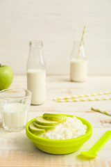 Plate with boiled rice and apple for child on table