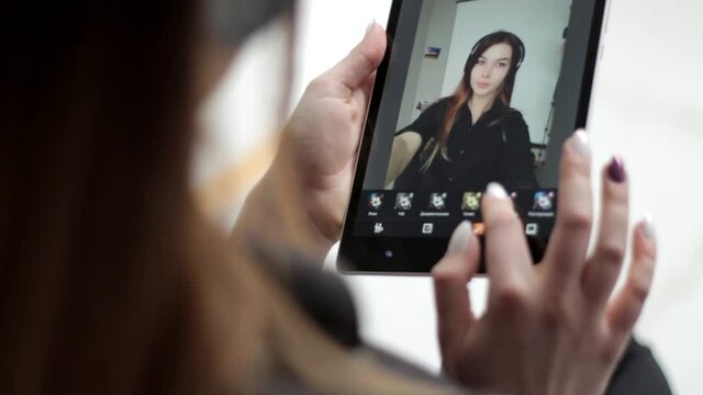 Good looking young lady editing applying filters on her selfie photographs on multitouch screen tablet