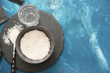 Bowl with rice and glass of water on color background