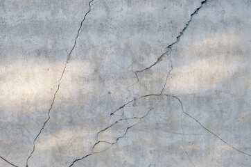 Fragment of gray concrete wall with sun glare and chaotically diverging in different directions,...