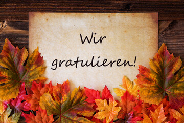 Old Paper With German Text Wir Gratulieren Means Congratulations. Colorful Leaves Autumn Decoration