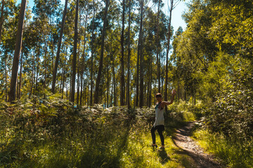 Obraz premium A young woman waving on the path between trees in the Listorreta Natural Park in the town of Errenteria in the park of the Peñas de Aya or Aiako Harria park. Gipuzkoa, Basque Country