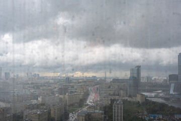a view of a big city through the window where you can see that it is raining outside