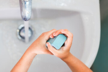 washing children's hands under running water in the sink . hygiene and health concept