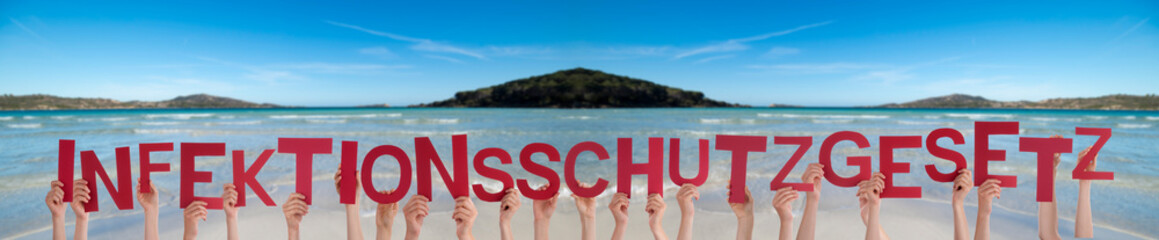 People Hands Holding Red German Word Infektionsschutzgesetz Means Infection Law. Ocean And Beach As Background