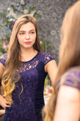 Naklejka premium The girl picks up a dress looking in the mirror.