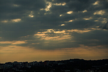 beautiful sunset with grey clouds on dramatic sky above cityscape silhouettes